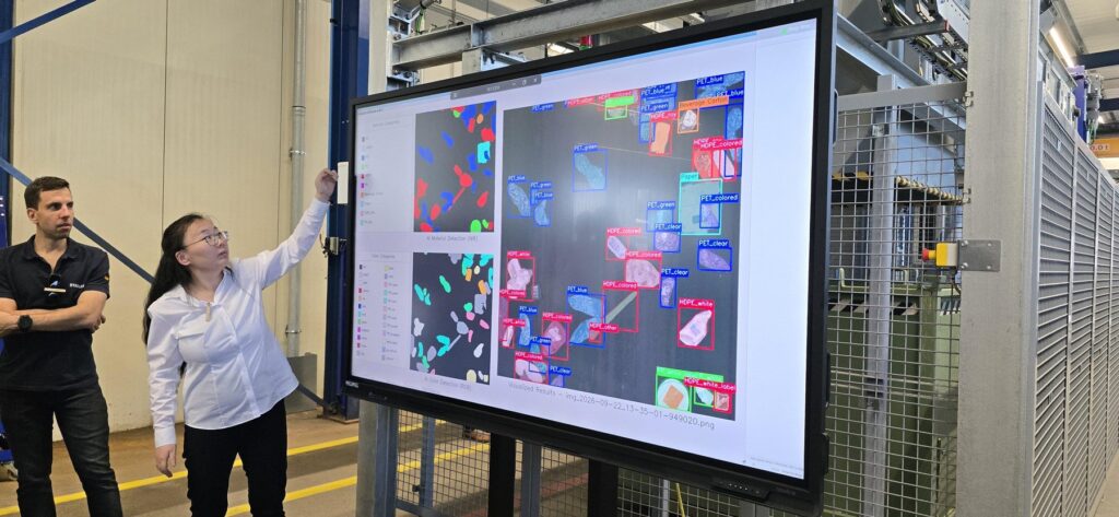 Engineer pointing at a screen showing AI material detection (NIR) and color detection (RGB) of plastic packaging labelled PET and HDPE