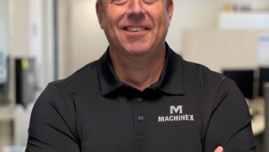 Portrait of Jon Gertsmeier smiling with arms crossed, wearing a black polo shirt with the Machinex logo