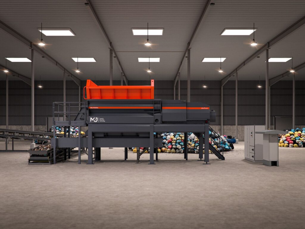 Side view of the M&J P2000e electric pre-shredder with orange feed hopper, UltraBoost drive section, discharge conveyor and control cabinets, with piles of waste bags behind the machine
