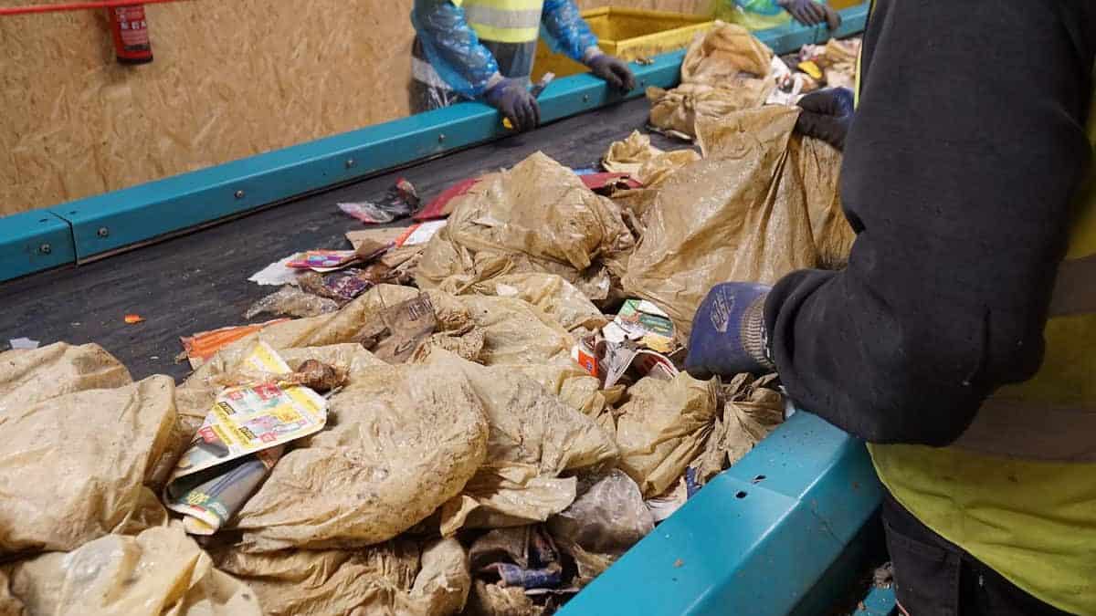 Workers in gloves sorting paper and plastic material on a conveyor belt