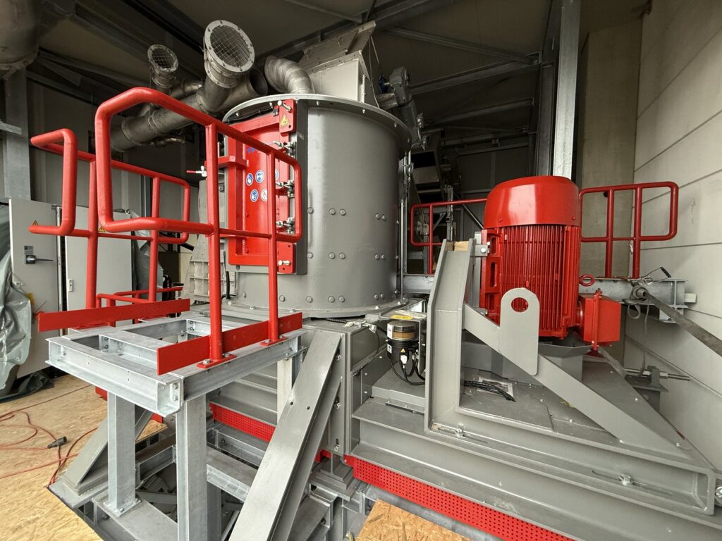 Grey cylindrical THM machine housing with red service door, red safety railings and a large red electric drive motor on a steel frame