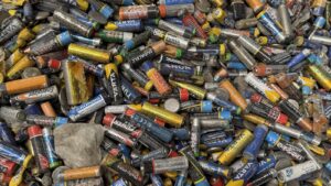 Close-up of a large pile of spent AA, AAA and button cell batteries of many brands collected for recycling