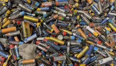 Close-up of a large pile of spent AA, AAA and button cell batteries of many brands collected for recycling