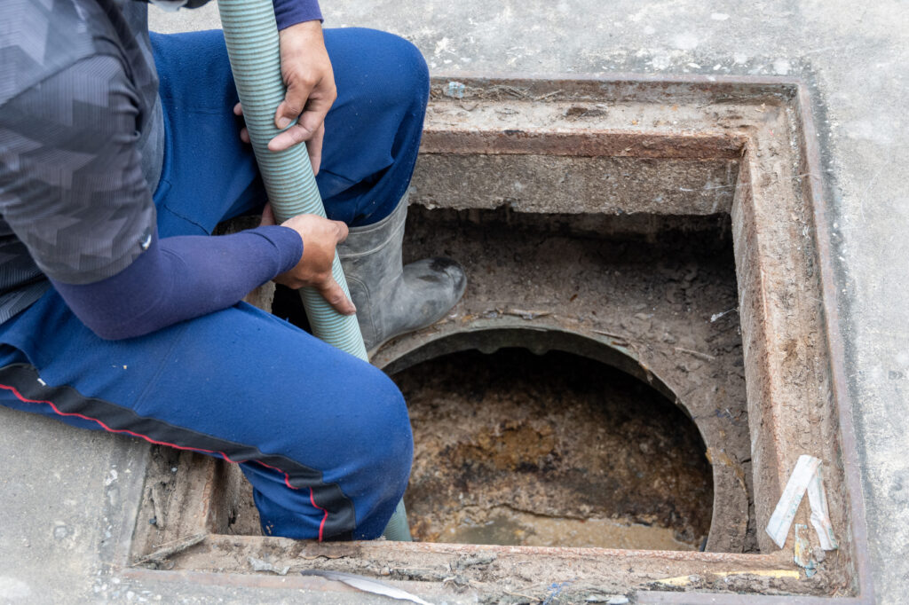 Worker carrying a suction hose to a vacuum truck for liquid waste and grease collection
