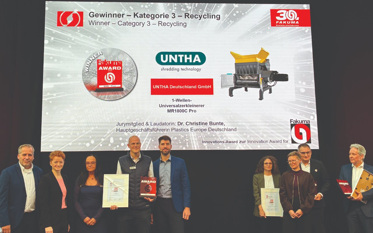 Award ceremony on a trade fair stage: a group of people with certificates in front of a large screen showing the FAKUMA Innovation Award for the Recycling category