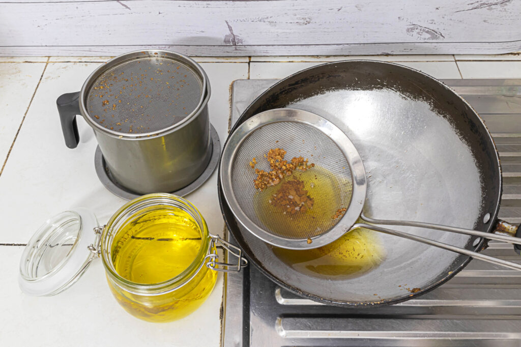 Used cooking oil in a pan and glass jars, collected for recycling into renewable fuel